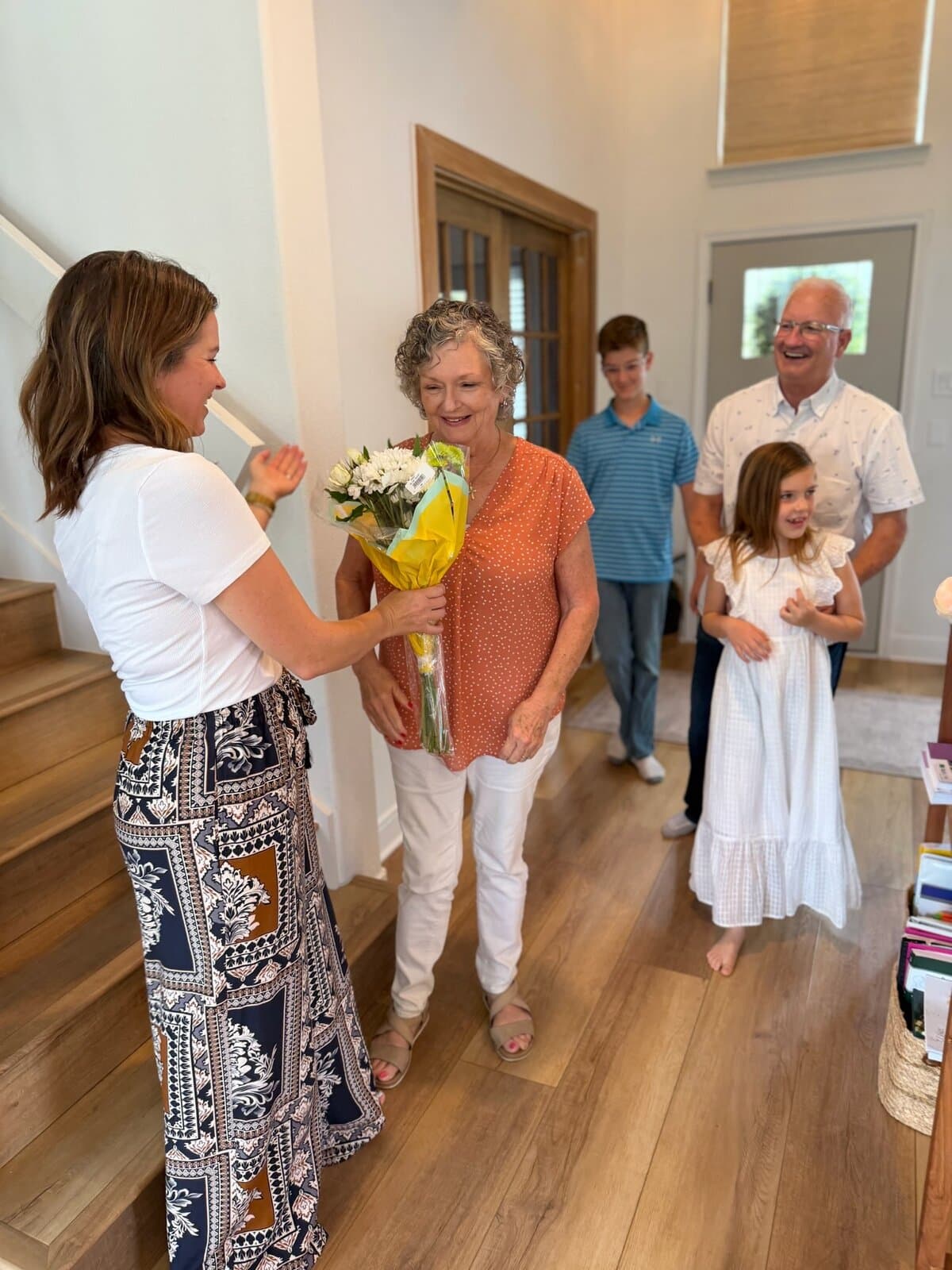 A daughter giving her mom (Grandma) a bouquet of flowers on Mother's Day, the family looking on