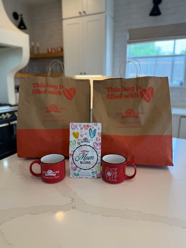 Two Just Love catering bags packed and ready for pickup with a Mom Blend coffee bag and ceramic mugs